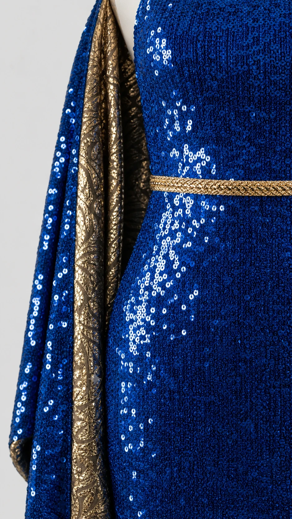 Dettaglio delle paillettes iridescenti blu e del bordino dorato lungo lo scollo
